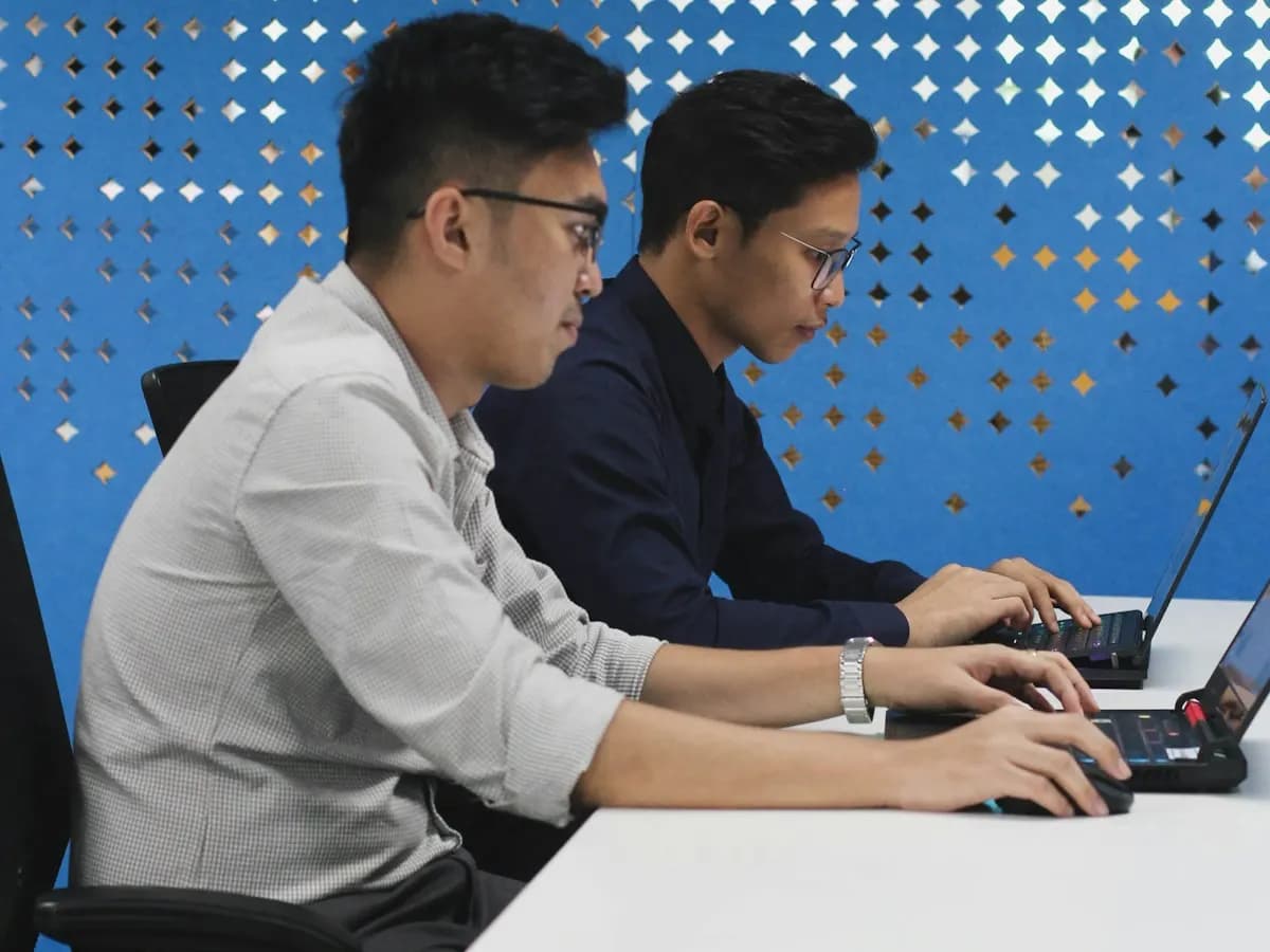 Deux collègues travaillant côte à côte sur leurs ordinateurs