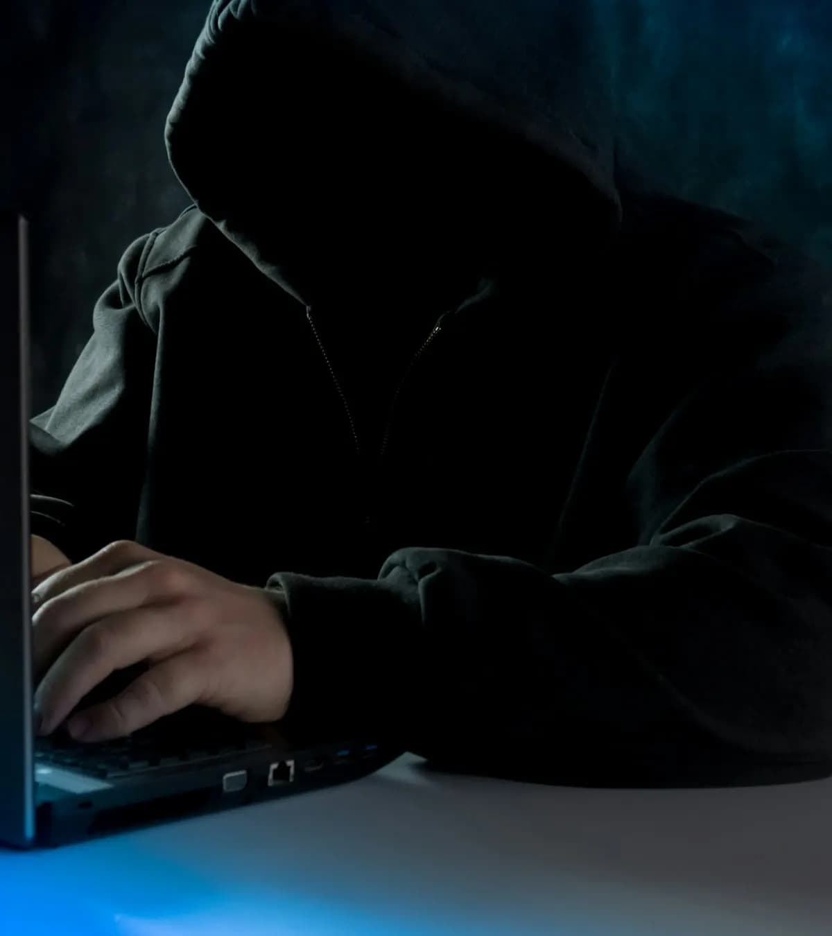 Personne encapuchonnée devant un ordinateur portable